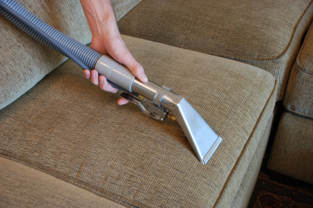 cleaning a febric sofa with the help of cleaner